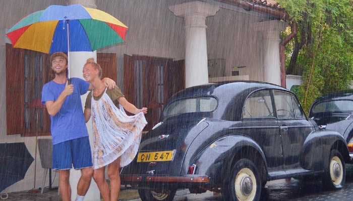 a couple with under an umbrella next to a classic car